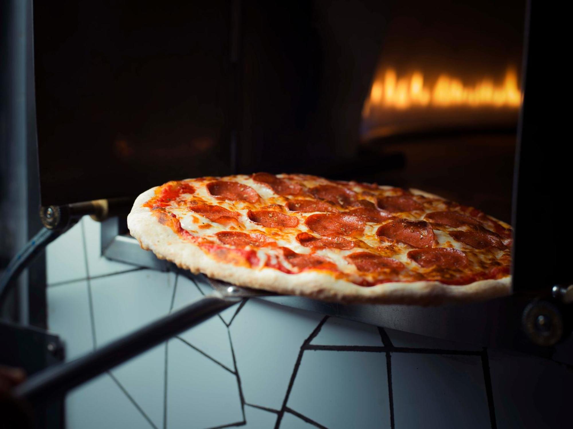 シェラトン ダンマン ホテル ＆ コンベンションセンター ダンマーム エクステリア 写真 Pizza being removed from a wood-fired oven